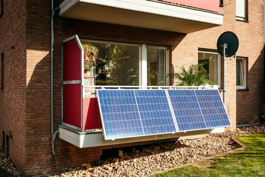 A small solar panel fixed to the balcony of a brick building