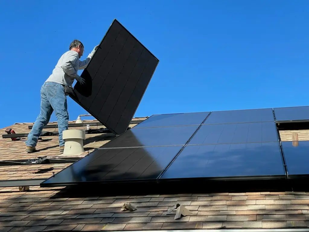 Installer fitting a solar panel on a roof