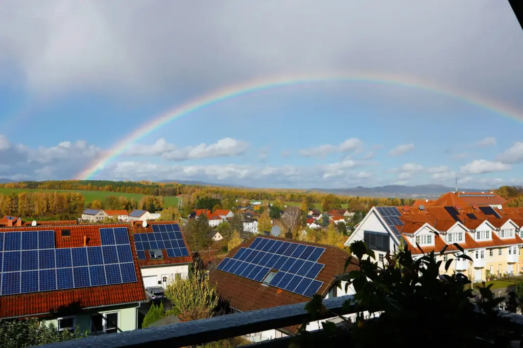 Houses with solar panels on their roofs under a rainbow